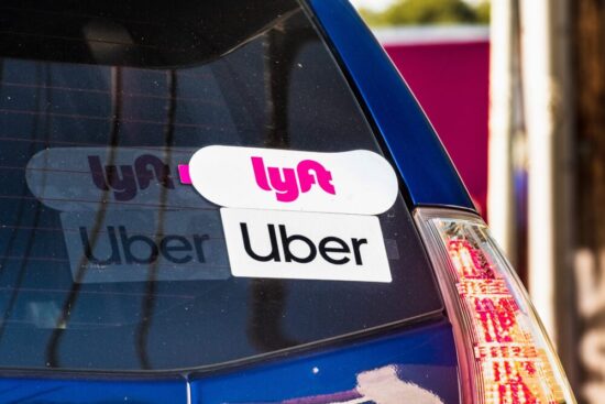 Back of a car with Lyft and Uber stickers on it.