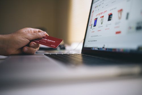 holding a credit card in front of a computer
