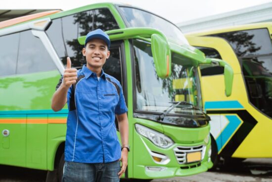 Man stands in front of a travel bus and gives a thumbs up.