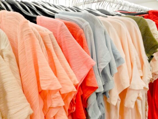 Colorful pink, salmon, and gray t-shirts hanging on a rack