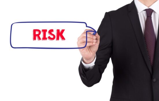 Person in a suit writing "risk" on a white board