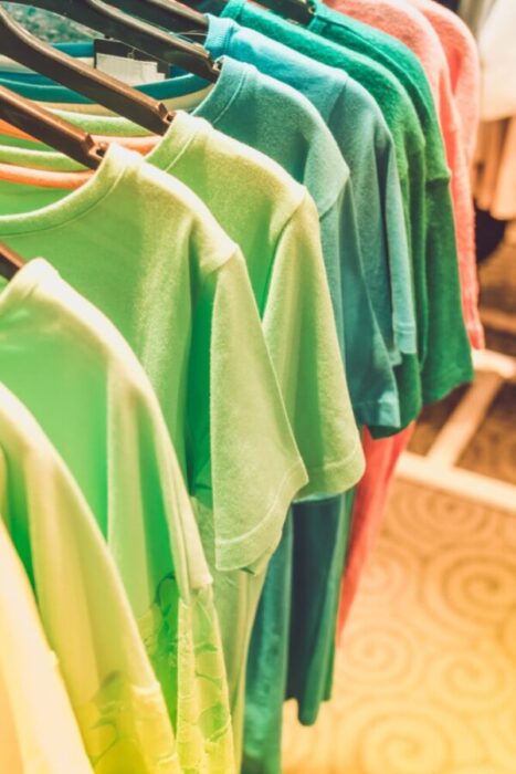T-shirts in shades of green hanging on a rack