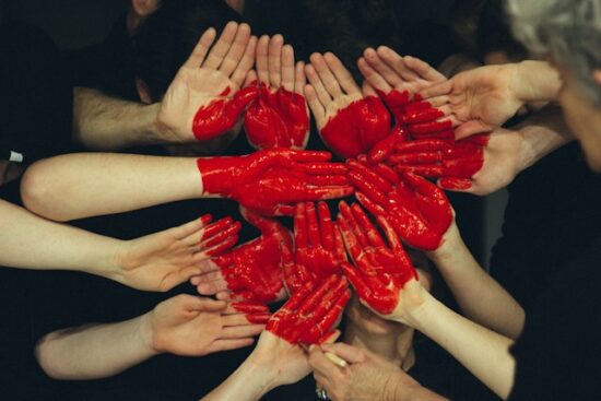 People holding outstretched hands painted red to make a heart