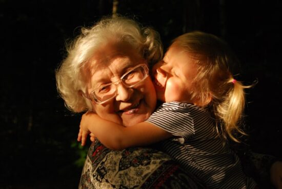 Elderly grandmother embracing her young granddaughter