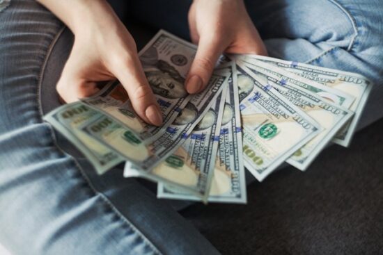 Person sitting cross-legged fanning out cash