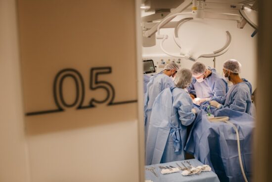 Looking through the door at a surgical team operating on someone.