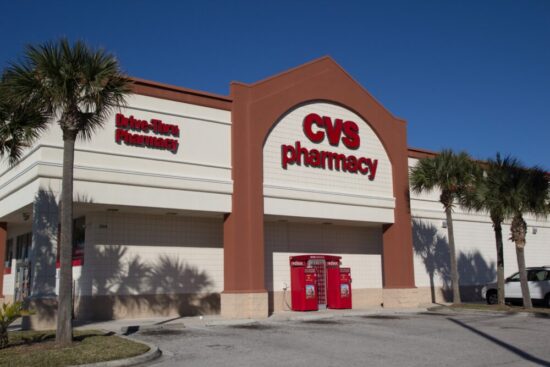 The front of a CVS store with palm trees as landscaping.