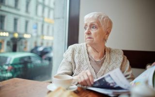 social security widow benefits - Tense woman with journal looking through window while sitting in cafe