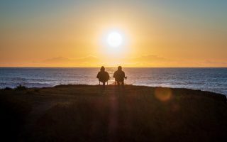 retired couple sitting and looking at the sunset