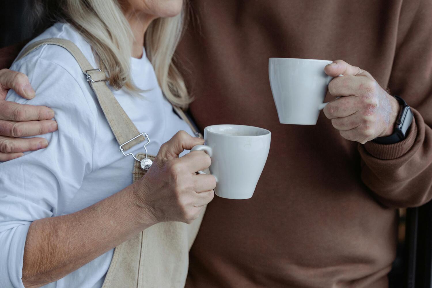 older couple embracing while holding a cup of coffee