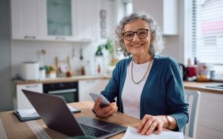 Happy mature lady using laptop to save money; evocative of things you don't need to pay for.
